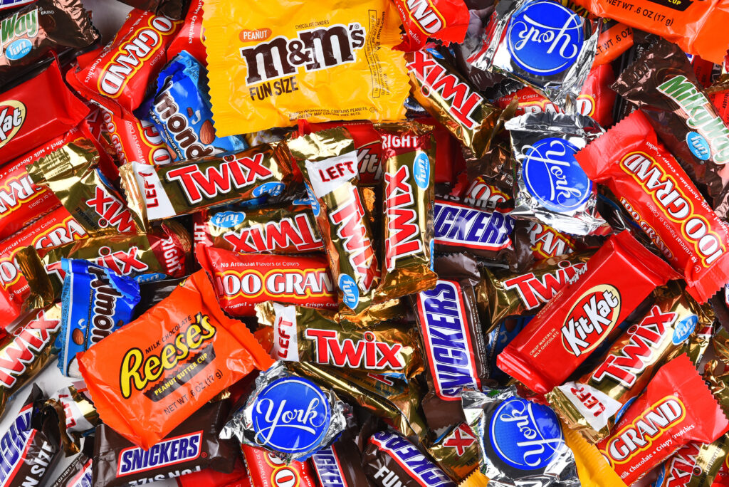 Assorted Halloween candy including M&Ms, Twix, Snickers, Reese's, KitKat, and other chocolate bars in colorful wrappers