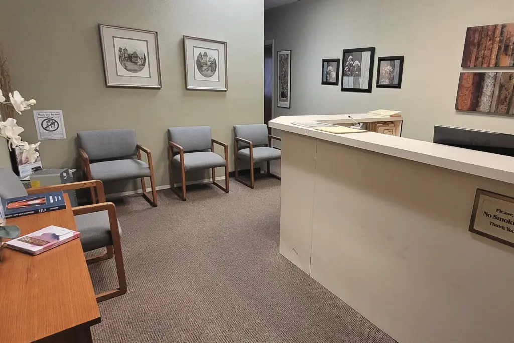 The waiting area: grey upholstered chairs, white orchids and the reception counter with its name plate